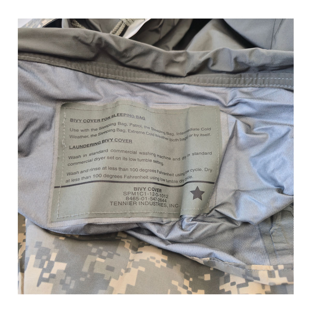 Bivy cover with label on a sleeping bag, featuring digital camouflage pattern.